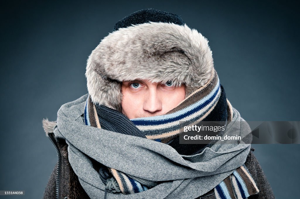 Man in winter clothes is tightly bundled up, cap, scarves