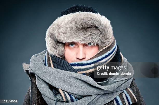 man in winter clothes is tightly bundled up, cap, scarves - cold stock pictures, royalty-free photos & images