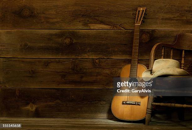 country und western-musik-szene mit sessel, hut und gitarre-barnwood hintergrund - country and western music stock-fotos und bilder