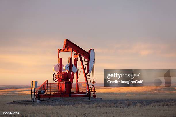 red prairie pumpjack in alberta oil field - oil industry stock-fotos und bilder
