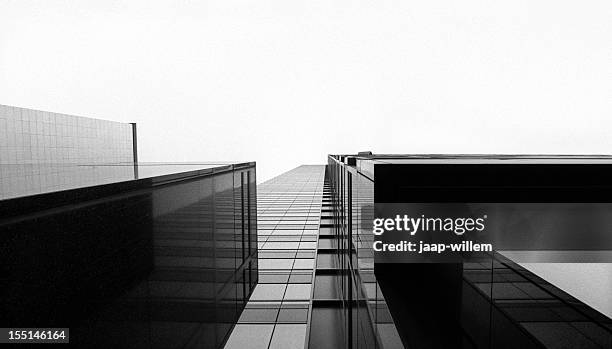 looking up at a glass skyscraper - black-and-white stockfoto's en -beelden