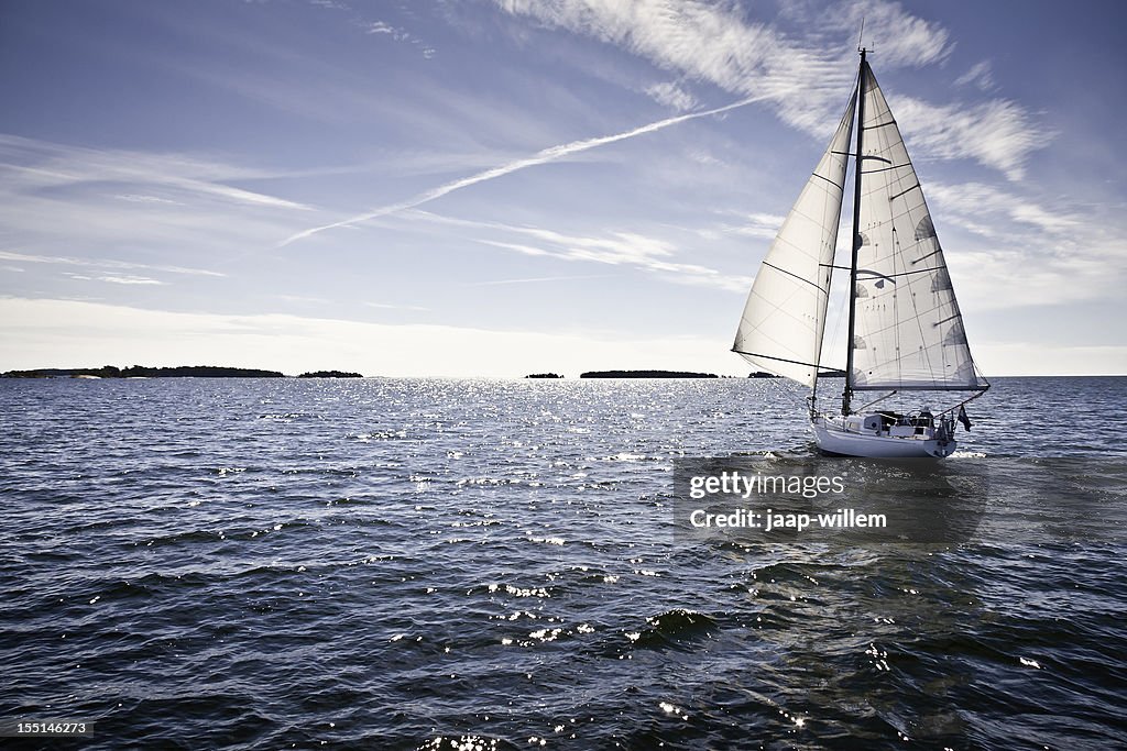 Classic yacht sailing away against blue sky
