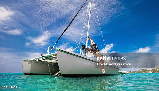 tropical vacation: man diving off sailboat - catamaran stockfoto's en -beelden
