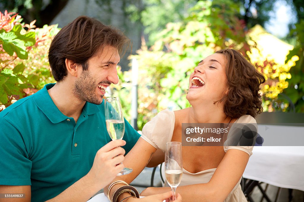 Happy Italian couple laughing in an outdoor restaurant