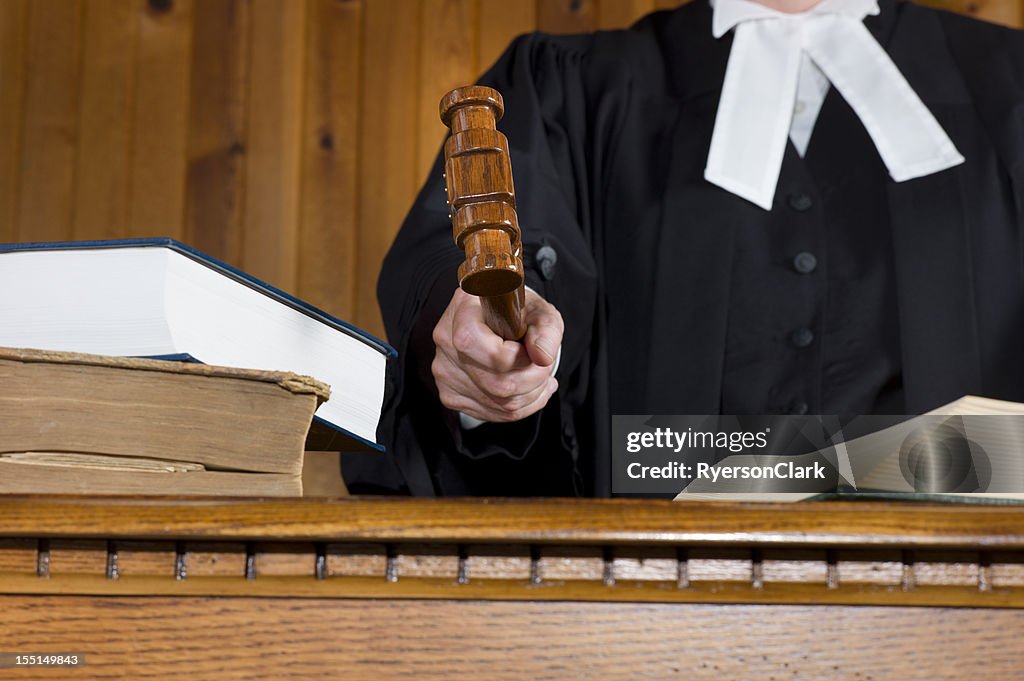 Judge In Traditional Court Robes Using the Gavel.
