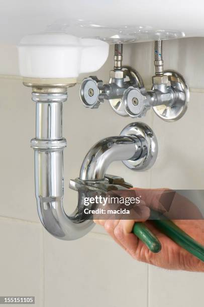 hand of a plumber fixing a sink with green tool - water pipe stock pictures, royalty-free photos & images