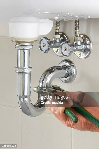 hand of a plumber fixing a sink with green tool - sink stock pictures, royalty-free photos & images