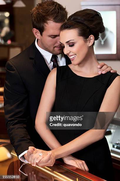 adorable young couple shopping for diamond ring in jewelry store - cosmetics counter stock pictures, royalty-free photos & images