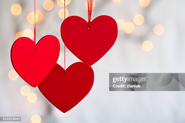 three hanging red hearts on defocused light background. - valentijnsdag stockfoto's en -beelden