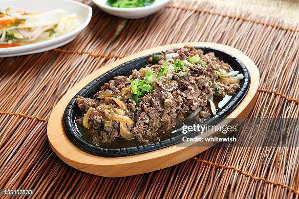 bulgogi on a wooden platter on a straw table - korean food stock pictures, royalty-free photos & images