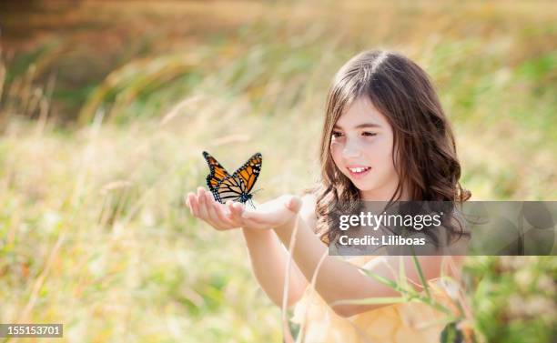 mädchen in feld mit einem monarch-schmetterling - butterfly hand stock-fotos und bilder