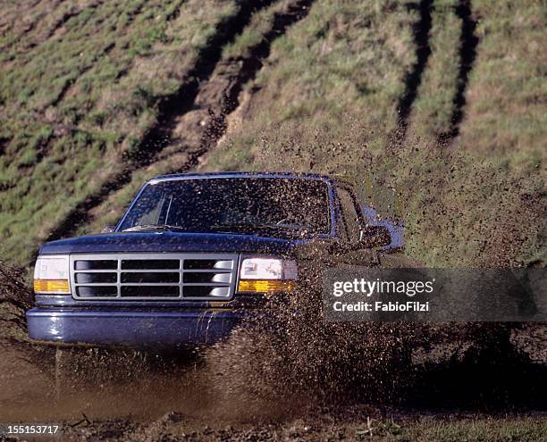 blue pick up truck driving through a mud puddle - mud truck stock pictures, royalty-free photos & images