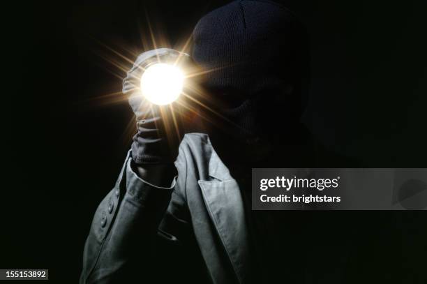 ladrón sosteniendo una linterna en la oscuridad - clave baja fotografías e imágenes de stock