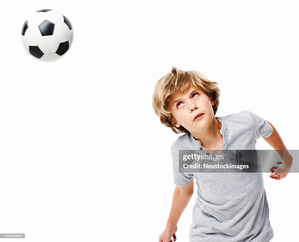 Garçon en direction de ballon de football, isolé
