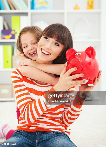 mutter und tochter mit sparschwein. - spardose stock-fotos und bilder