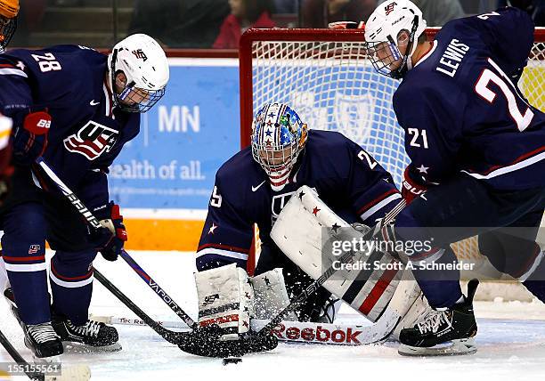 Shane Eiserman, Thatcher Demko and Clint Lewis of the United States U-18 team try to control a loose puck against the University of Minnesota October...