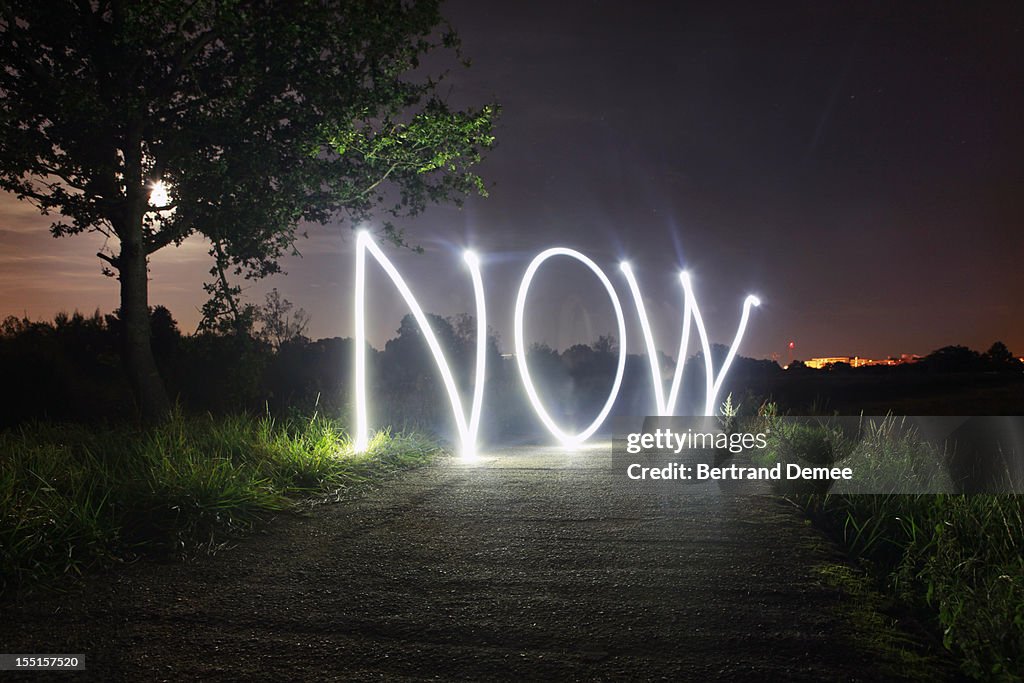 'Now' written in light