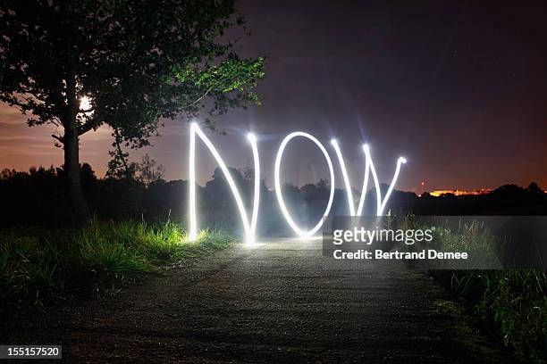 'now' written in light - today single word stock pictures, royalty-free photos & images