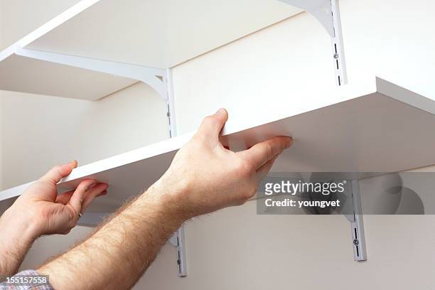 a tradesman installing hanging shelves - hanging bildbanksfoton och bilder