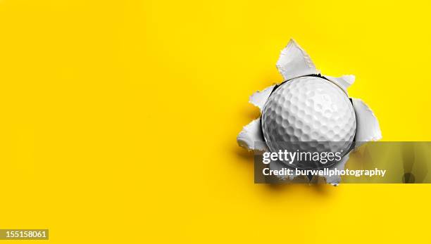 golf ball feststecken in gelbes papier - paper ball stock-fotos und bilder