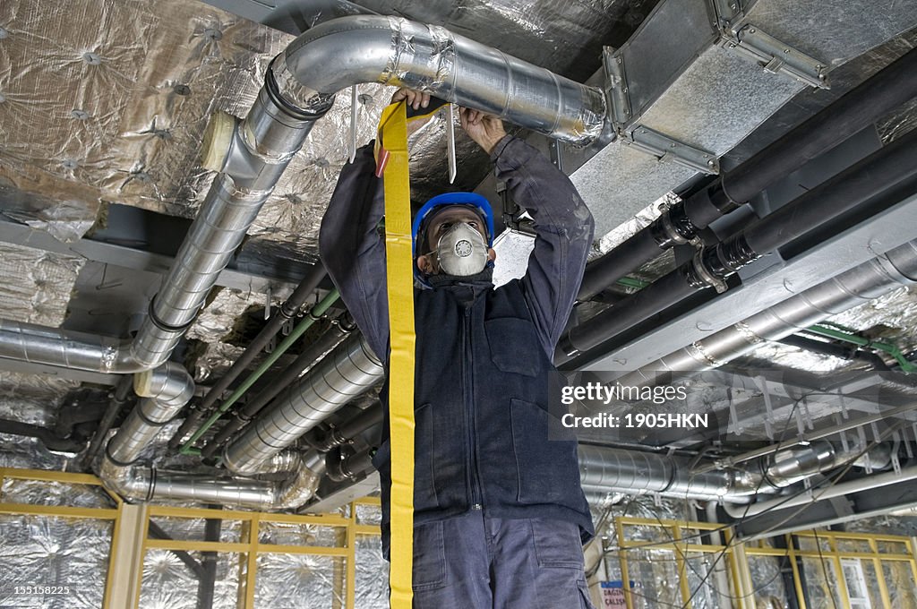 Worker wrapping an HVAC air duct with foil tape