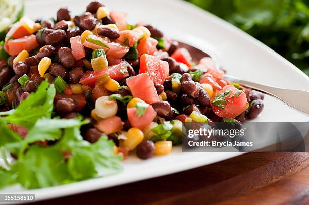 black bean salad on white plate siting horizontally on table - black beans stock pictures, royalty-free photos & images