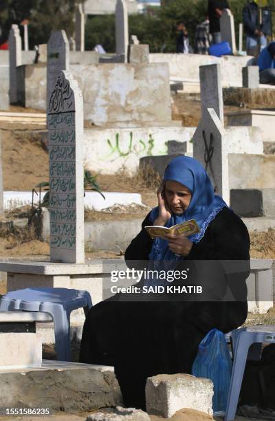 Palestinians woman recites the Fatiha, the opening Surat of the Koran, near the graves of relatives, a ritual performed by Muslims during the early...