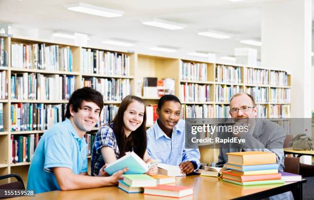 three students and lecturer in library look up smiling - rea001 stock pictures, royalty-free photos & images