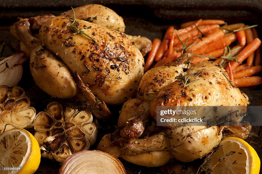 Two chicken roasts with carrots, onions and lemons