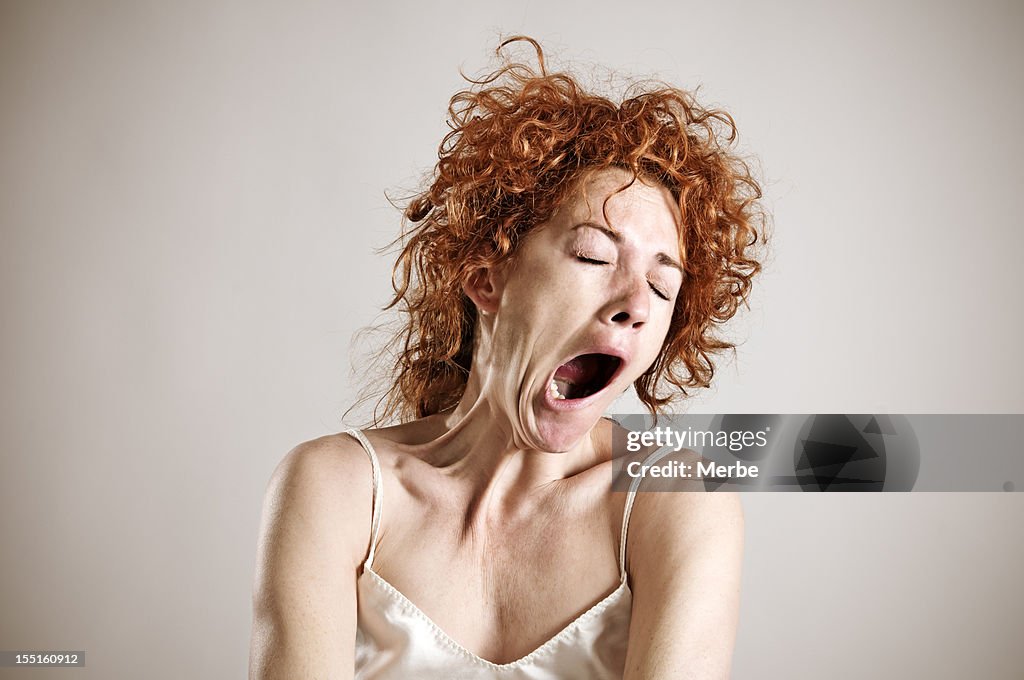 Yawning red haired woman in silk shirt
