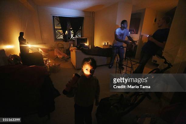 Lavell Harrington plays while shining a flashlight in his apartment lit with candles and without power or water in the Jacob Riis housing projects in...