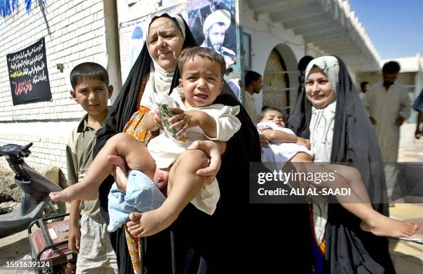 Iraqis carry their sons after they were freely circumcised 26 June 2005, at the Sadr cultural centre in Al-Amil, a Baghdad's poor working-class...