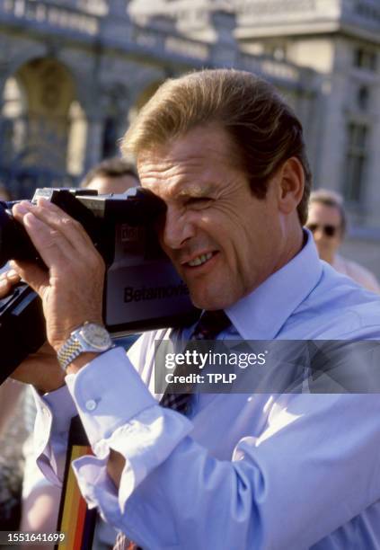 English actor Roger Moore , stands behind the camera during the filming of the 1985 James Bond spy movie, A View to a Kill in London, England, August...