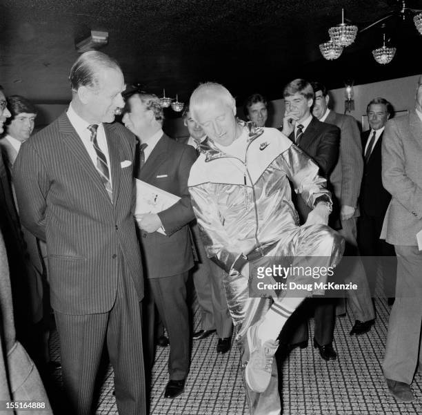 English television presenter Jimmy Savile shows the Duke of Edinburgh a cigar which he keeps tucked into his sock, circa 1985.