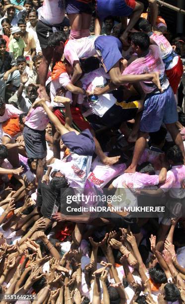 People watch devotees of Hindu God Lord Krishna tumble in the process of making a human pyramid to break a "dahi-handi" during a contest in Mumbai,...