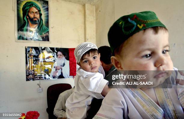 Iraqi babies wait for their turn to be circumcised for free 26 June 2005 inside a room decorated with posters of Imam Ali, the grandson of prophet...