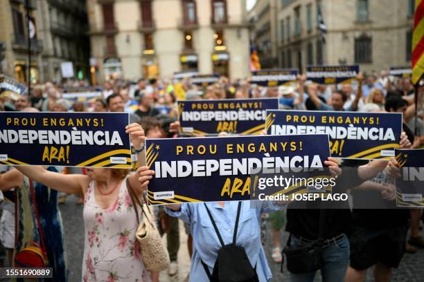 Demonstrators hold signs reading "Enough deception! Independence now !" as they take part in a protest called by the Catalan National Assembly a day...