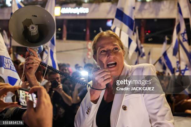 Former Israeli foreign minister Tzipi Livni speaks on a megaphone while surrounded by demonstrators blocking a highway during a protest rally against...