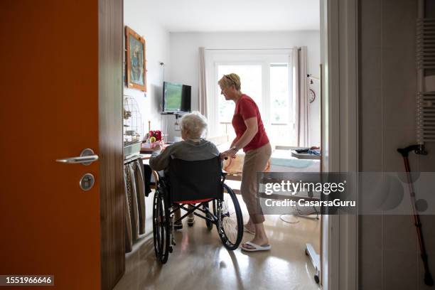 soignante et femme âgée en fauteuil roulant - besoin photos et images de collection
