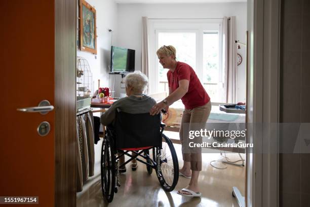 cuidador y una mujer mayor en silla de ruedas - vivienda-con-asistencia fotografías e imágenes de stock