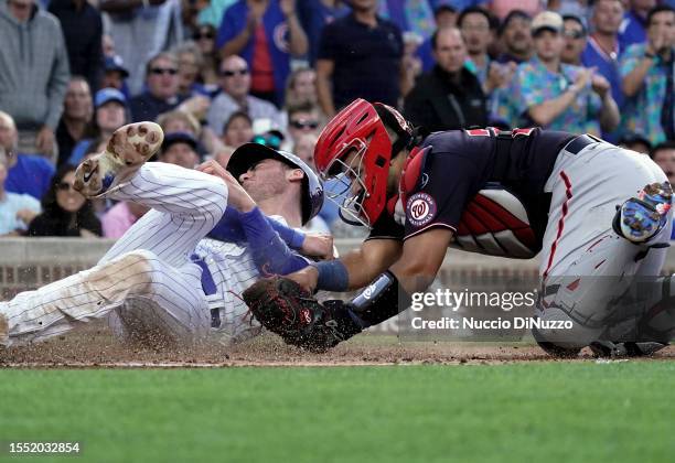 Cody Bellinger of the Chicago Cubs is safe at home against Keibert Ruiz of the Washington Nationals during the second inning of a game at Wrigley...