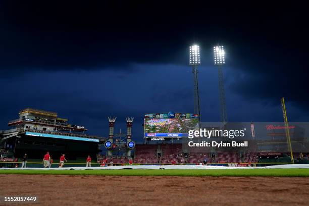 The grounds crew pulls the tarp onto the field during a weather delay during the game between the San Francisco Giants and the Cincinnati Reds at...