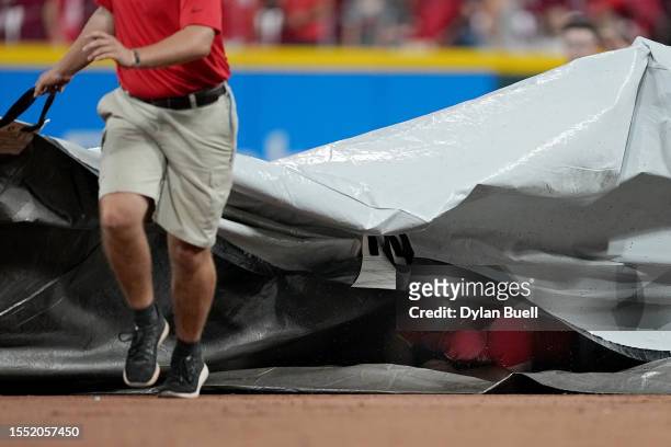 Member of the grounds crew falls underneath the tarp during a weather delay during the game between the San Francisco Giants and the Cincinnati Reds...