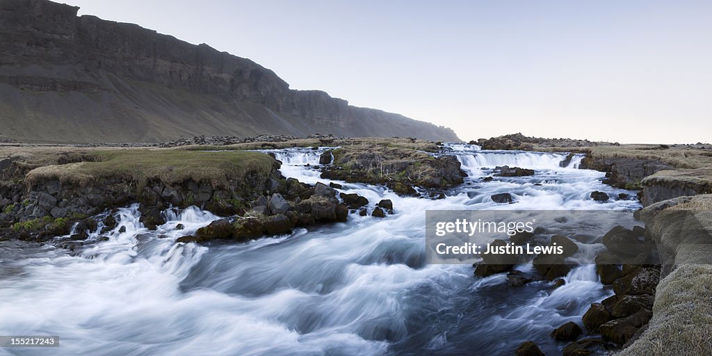 Rushing rocky river with mountain range behind