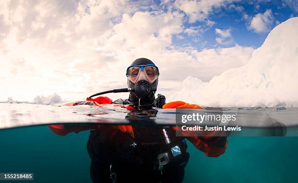 scuba diver next to an iceberg - split shot - buceo con equipo fotografías e imágenes de stock