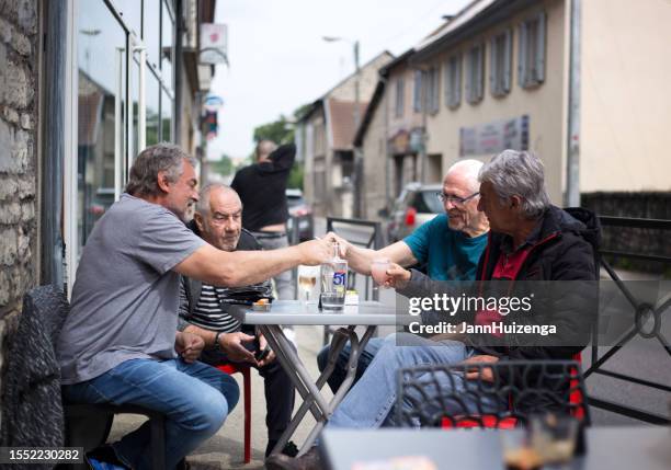 morestel, france: des hommes âgés trinquent au sidewalk cafe - morestel photos et images de collection