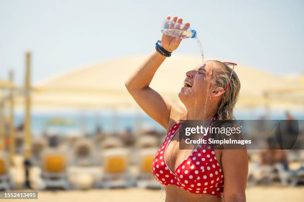 a young woman on the beach cools down with cold water during the summer heat. - hyperthermia stockfoto's en -beelden