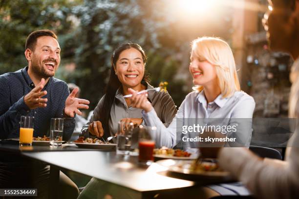group of happy colleagues talking while enjoying in lunch at a restaurant. - smart casual lunch stock pictures, royalty-free photos & images