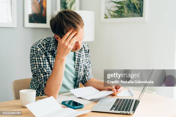 pensive male thinking about high prices. managing family finances. rise of utilities, gas, electricity, rental charges, water bill due to inflation and global crisis. facing downturn including energy. planning family budget while sitting in kitchen - energy bill stock pictures, royalty-free photos & images