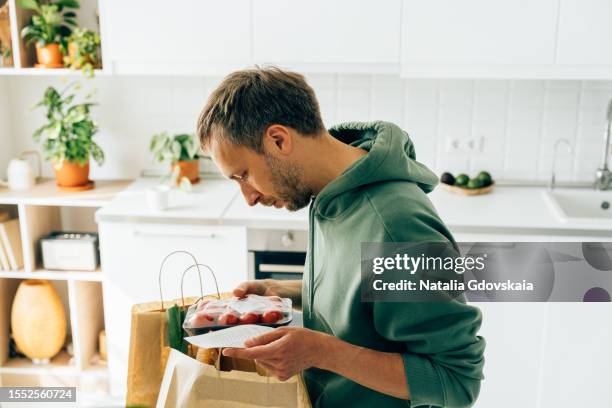 mature frustrated man looking at receipt from grocery store. rise in price of products concept. buying consumer goods during inflation. wisely planning family budget and managing expenses. living through economic downturn - grocery receipt stock pictures, royalty-free photos & images
